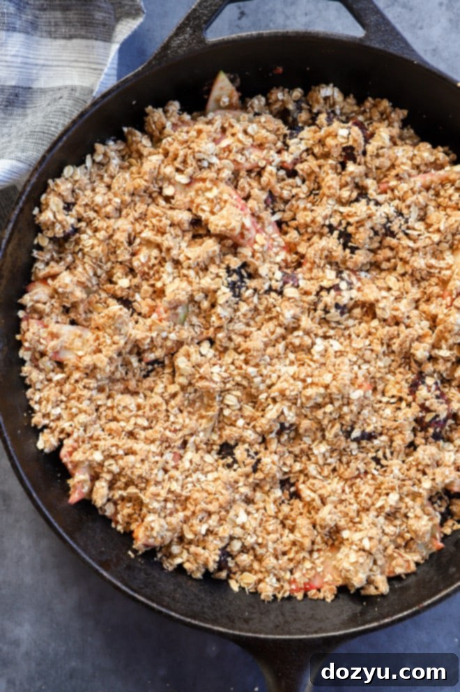 Image of an apple blackberry crumble in a skillet, topped with streusel, before baking