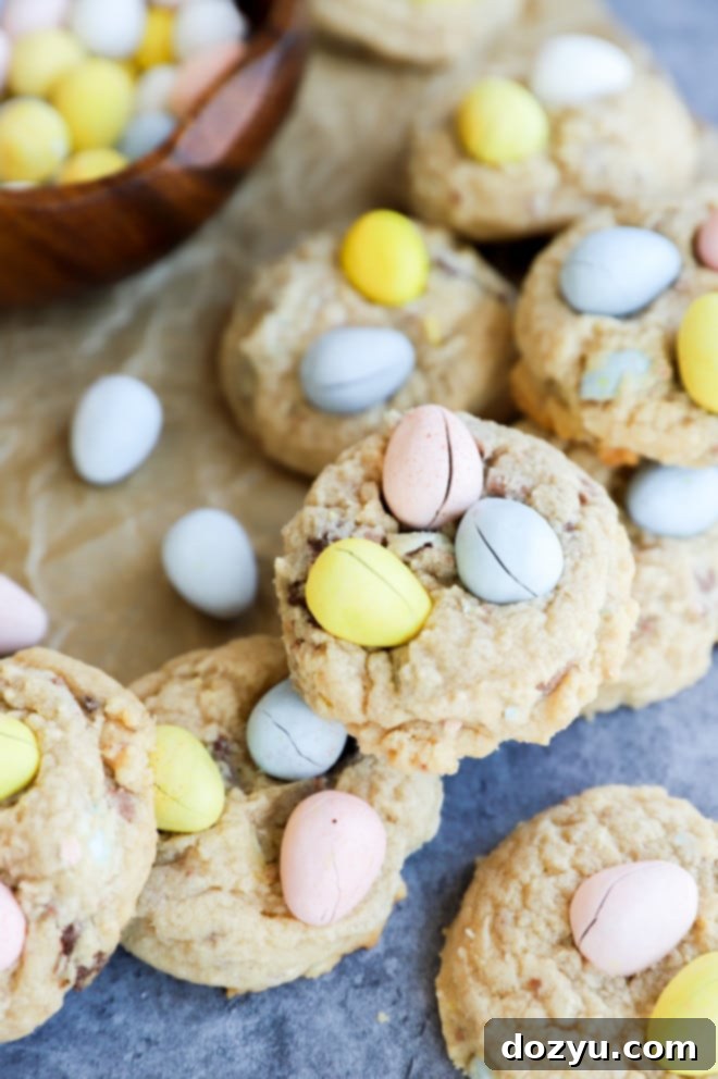 A lovely stack of Mini Eggs Cookies on parchment paper, adorned with extra Cadbury Mini Eggs, capturing the essence of Easter.