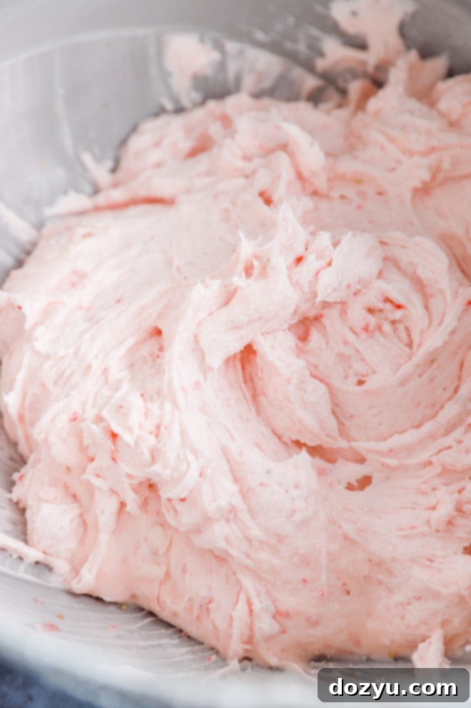 Creamy strawberry frosting beautifully swirled in a stand mixer bowl, ready for decorating