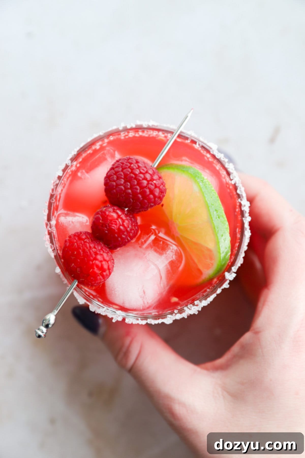 Hand holding a raspberry margarita in a glass image