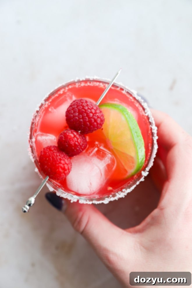 Hand holding a raspberry margarita in a glass image