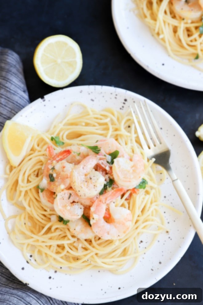 Roasted shrimp and lemon slices over spaghetti in a bowl