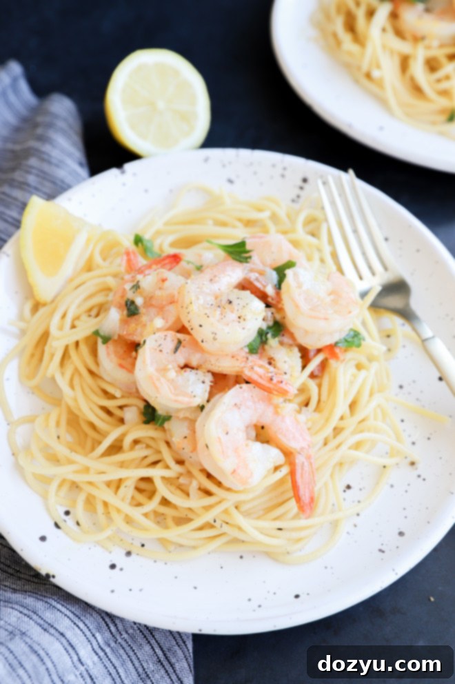Close-up side view of roasted shrimp and lemon slices on spaghetti