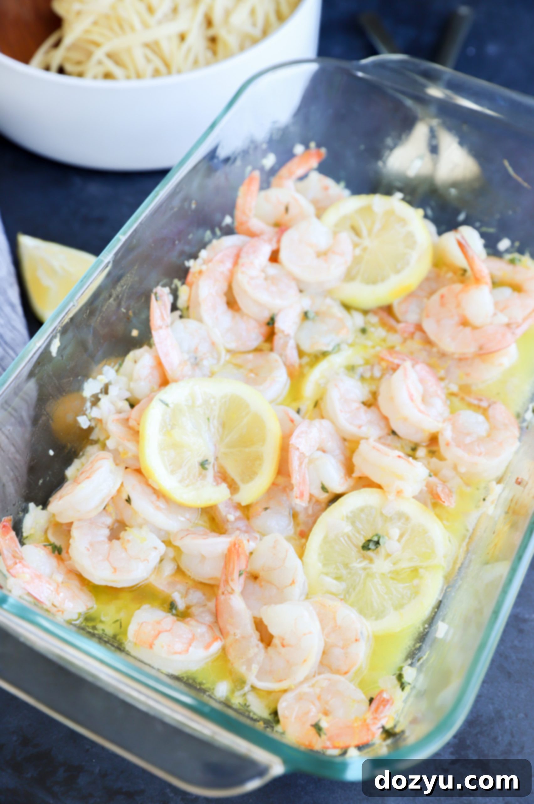 Close up photo of roasted garlic shrimp with lemon slices in baking dish