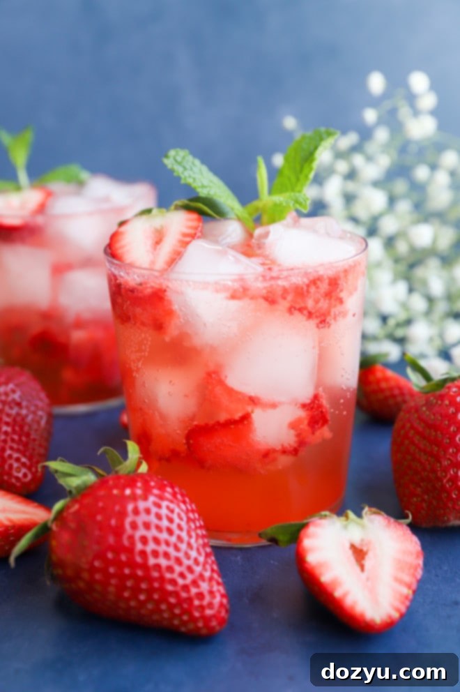 Close-up image of a Strawberry gin cocktail in a glass, showing muddled strawberries and ice.