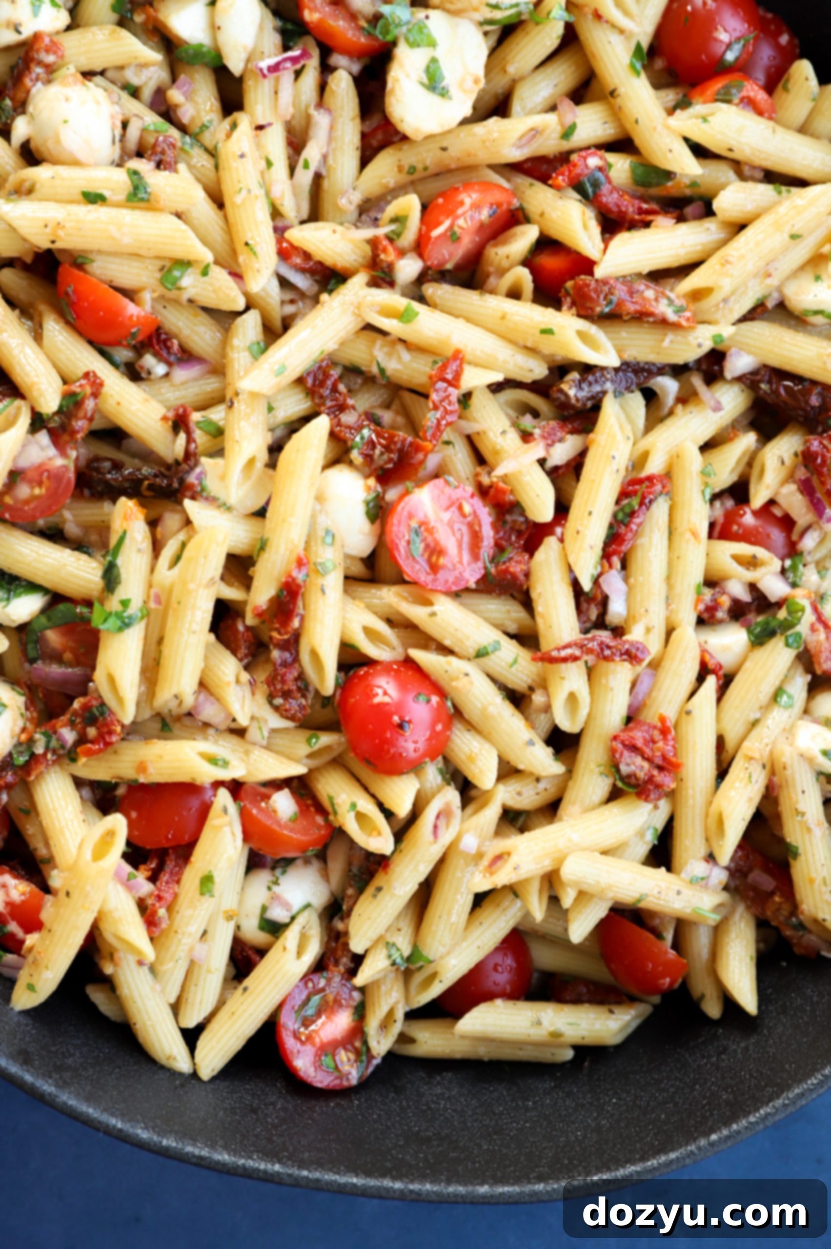 Image of a bowl of penne with vegetables and dressing