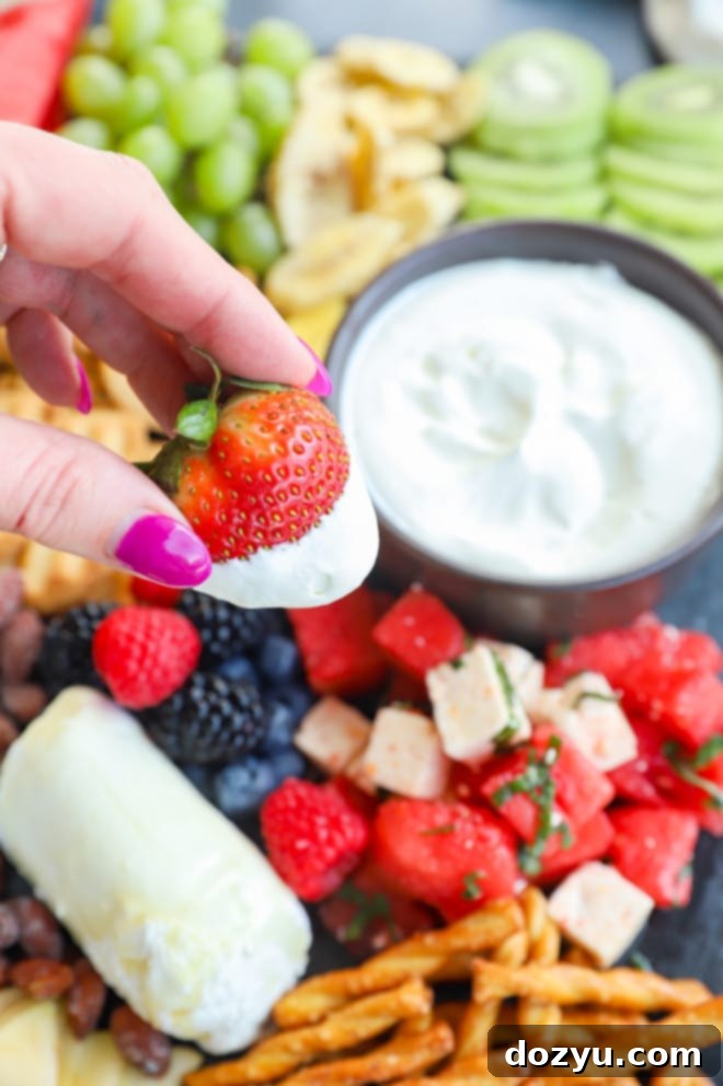 Dipping a strawberry in whipped cream with hand holding the strawberry picture