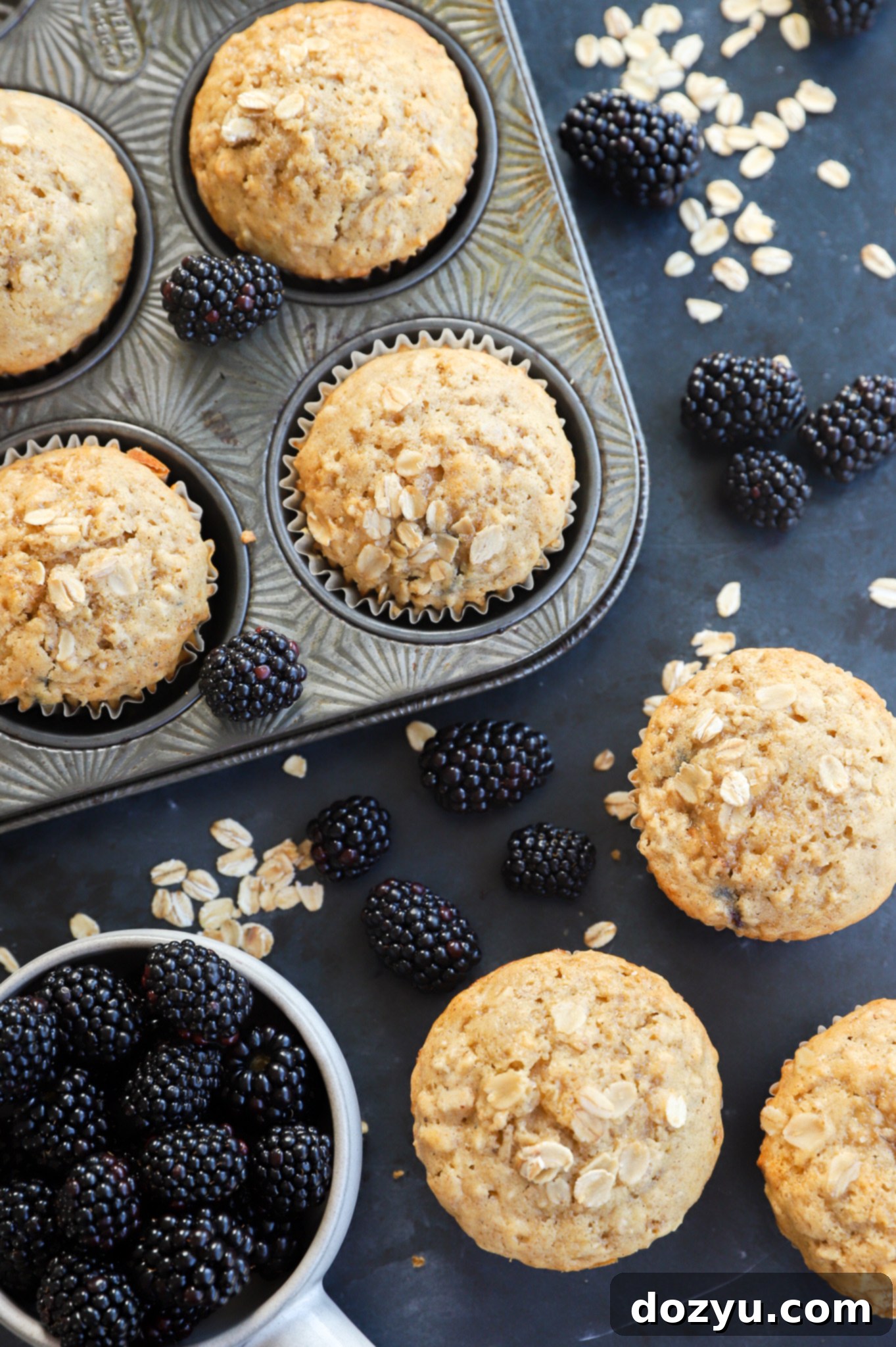 An overhead view of freshly baked Honey Blackberry Oatmeal Muffins in a cupcake tin, ready for serving.