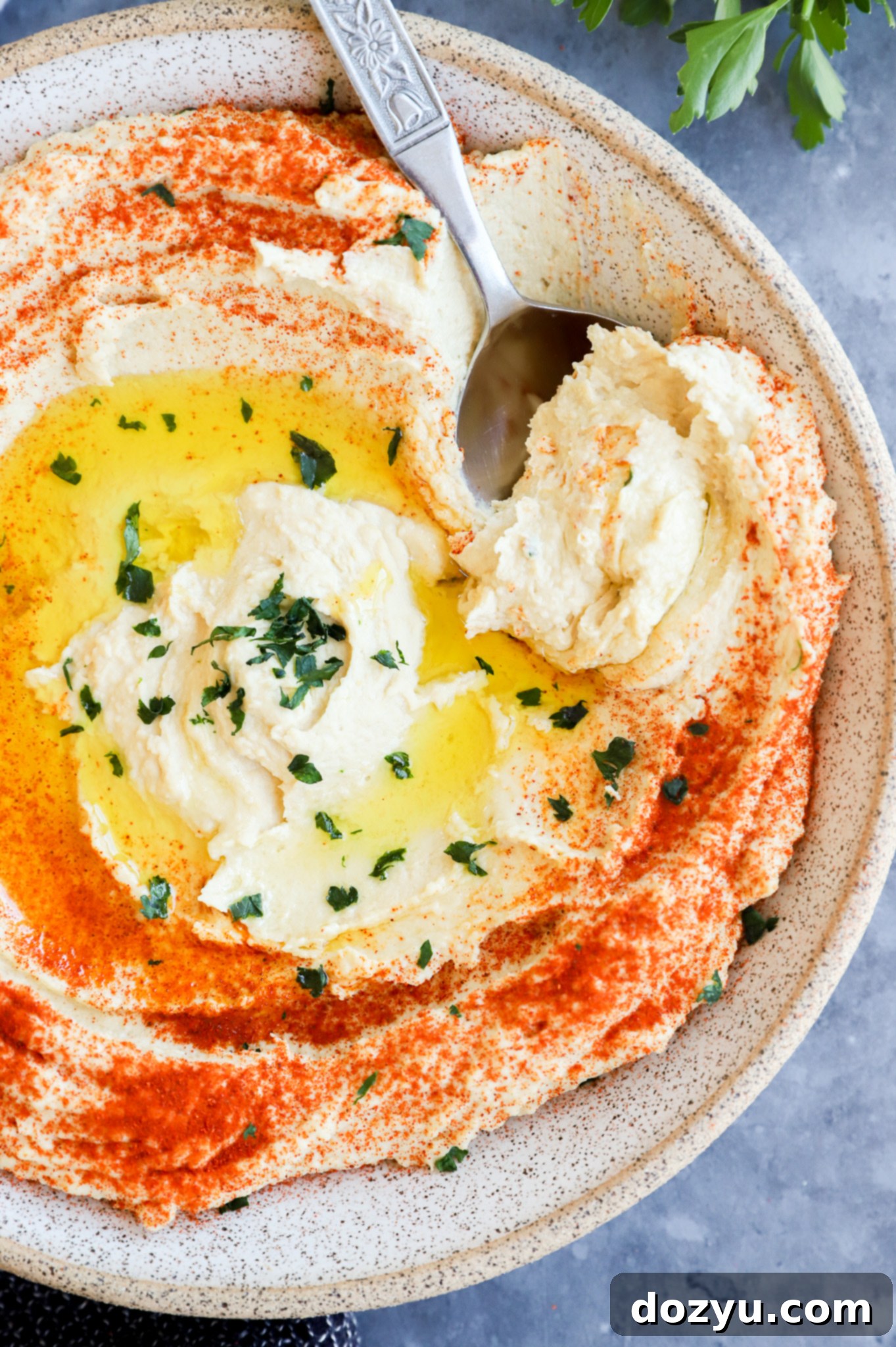 Scooping out a creamy chickpea dip from a bowl, highlighting its smooth texture