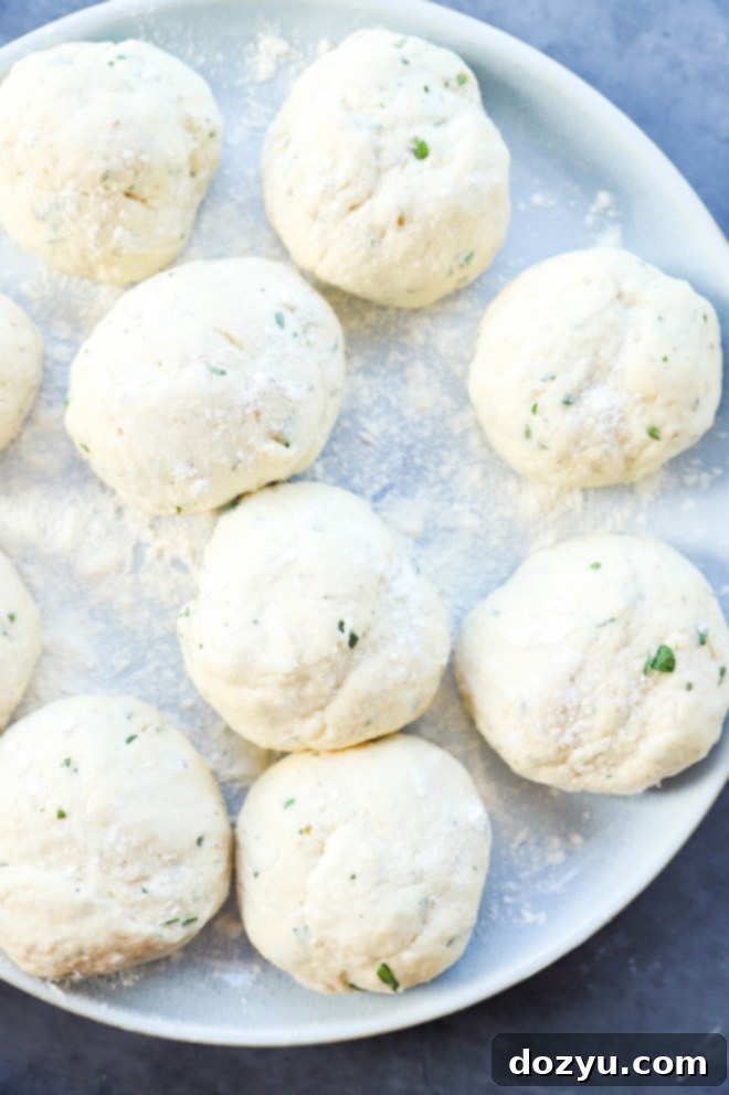 Hand-rolled Turkish bread dough formed into small, even balls on a flour-dusted plate, covered with a kitchen towel.