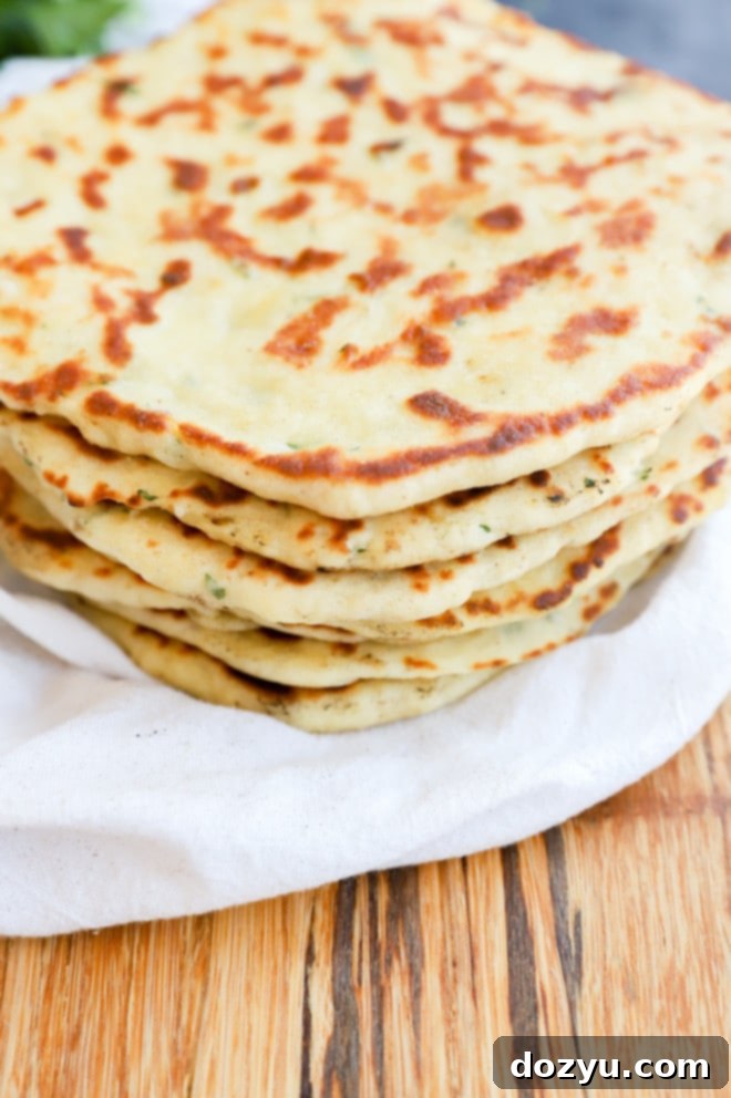 A pile of warm, soft Turkish bread (Bazlama) wrapped in a kitchen towel to keep it warm, showcasing its inviting texture.