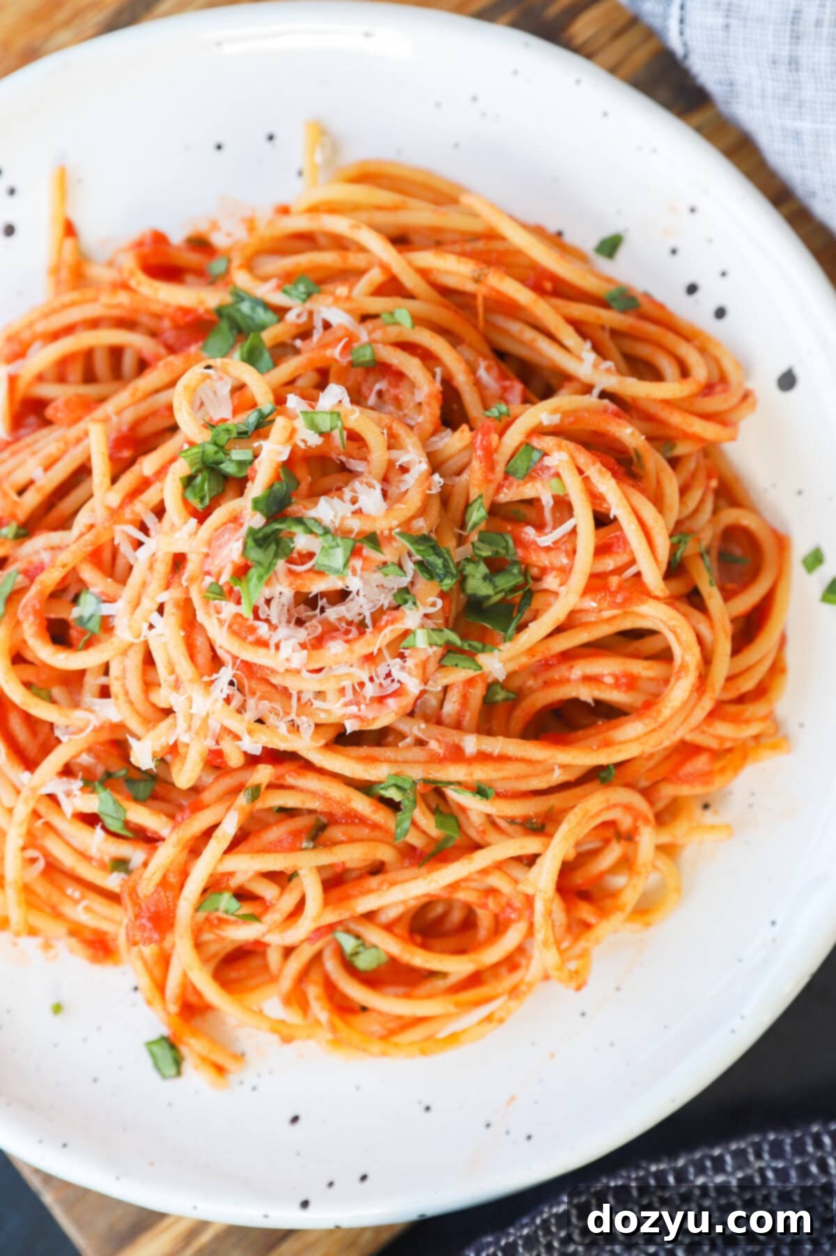 A beautifully presented plate of pasta napolitana, garnished with fresh basil leaves and a sprinkle of parmesan cheese, ready to be enjoyed.