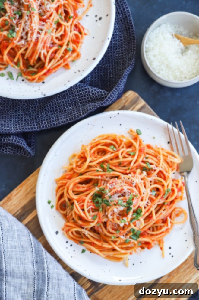 A serving of Italian spaghetti with vibrant tomato sauce and fresh basil on a white plate, ready to be eaten.