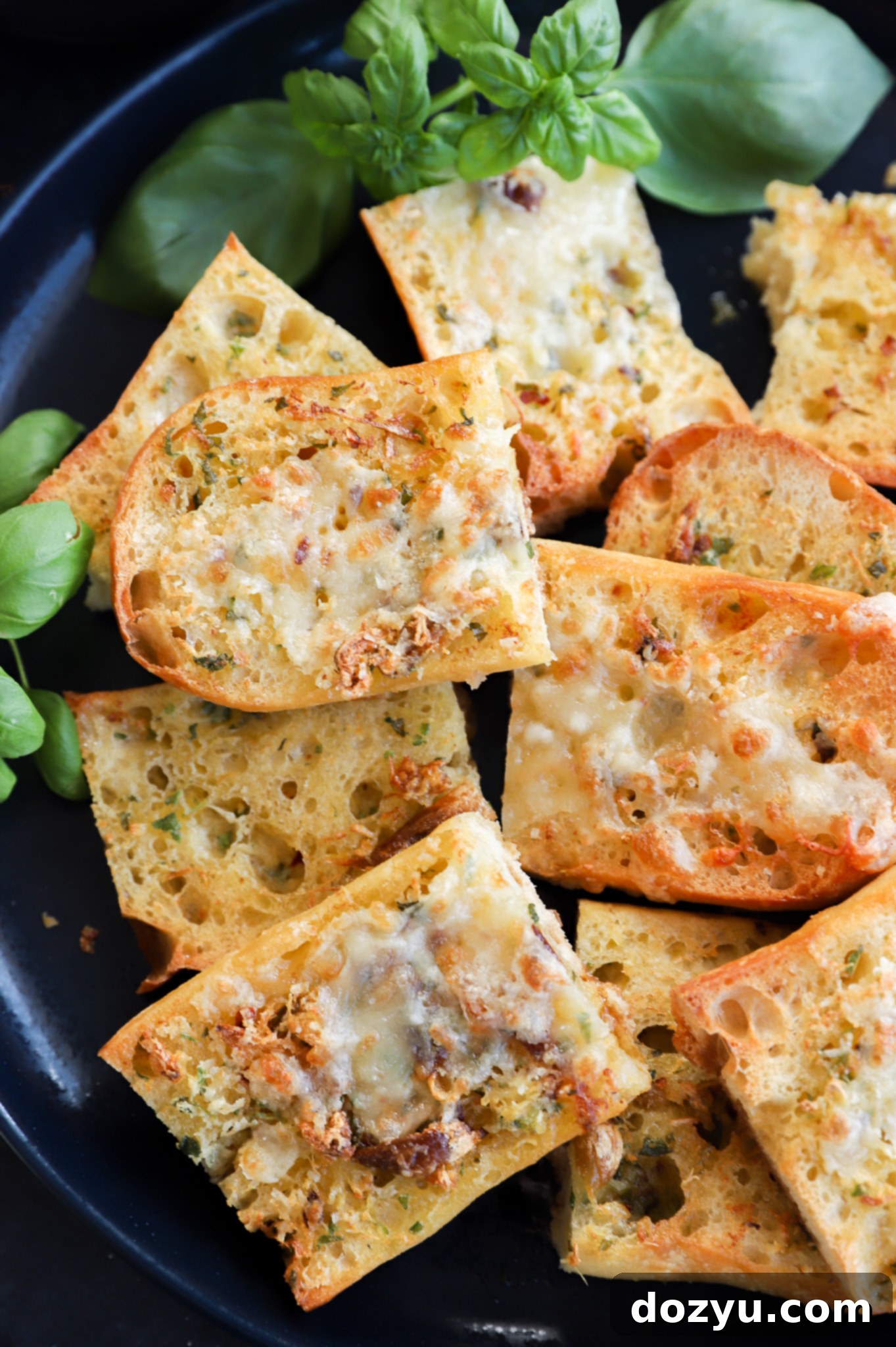 A platter of golden-brown toasted garlic bread slices, some topped with melted cheese, ready for serving.