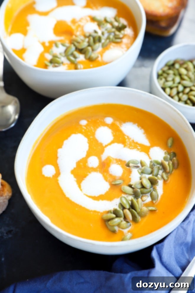 Two bowls of creamy sweet potato soup garnished with pumpkin seeds