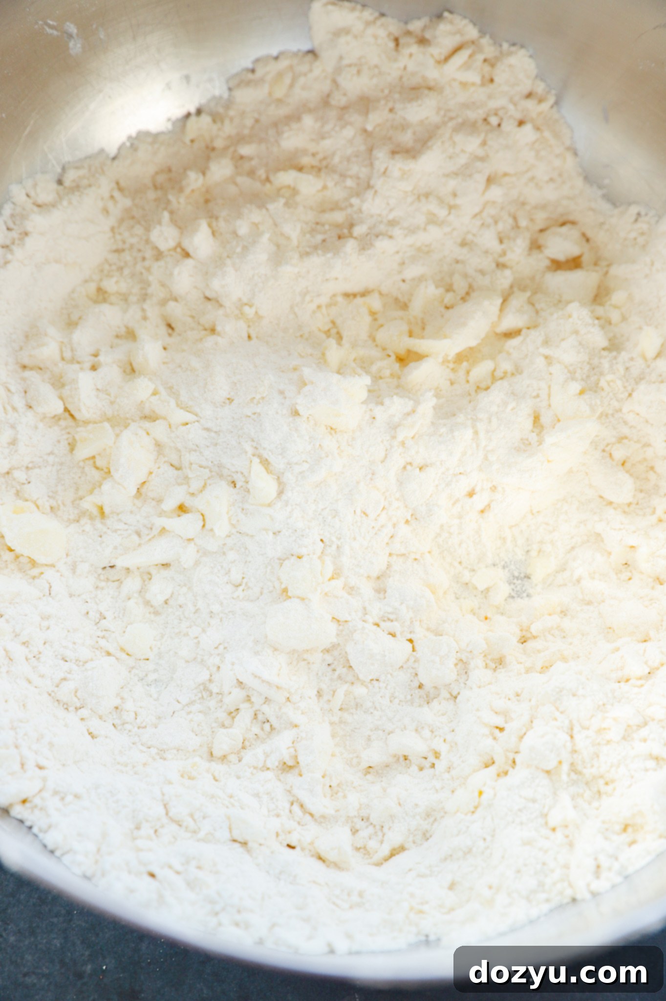 A large mixing bowl filled with biscuit dough, being gently mixed, showing the texture before kneading.