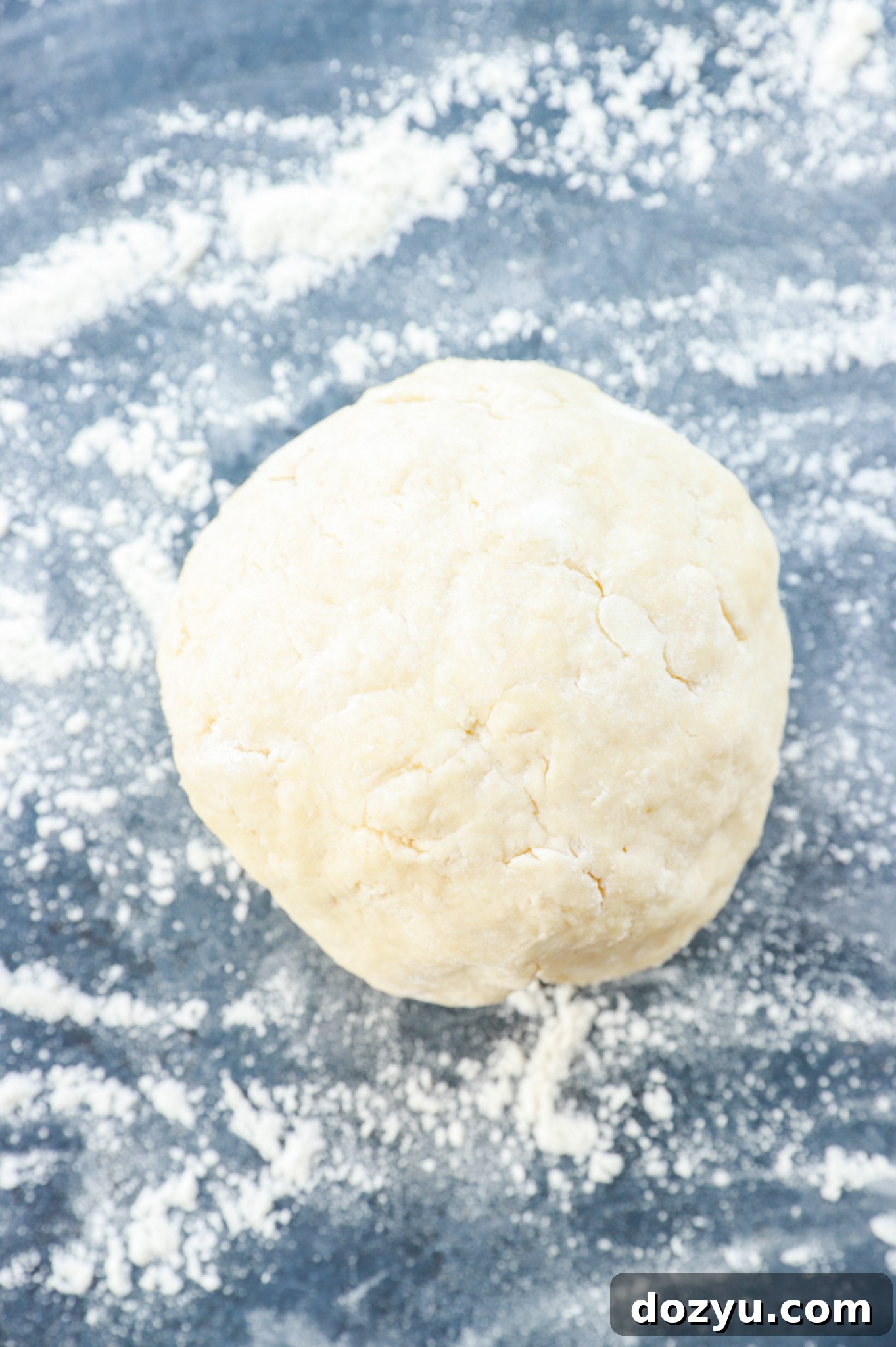 Unbaked biscuit dough, rolled out and ready for cutting, resting on a lightly floured surface.