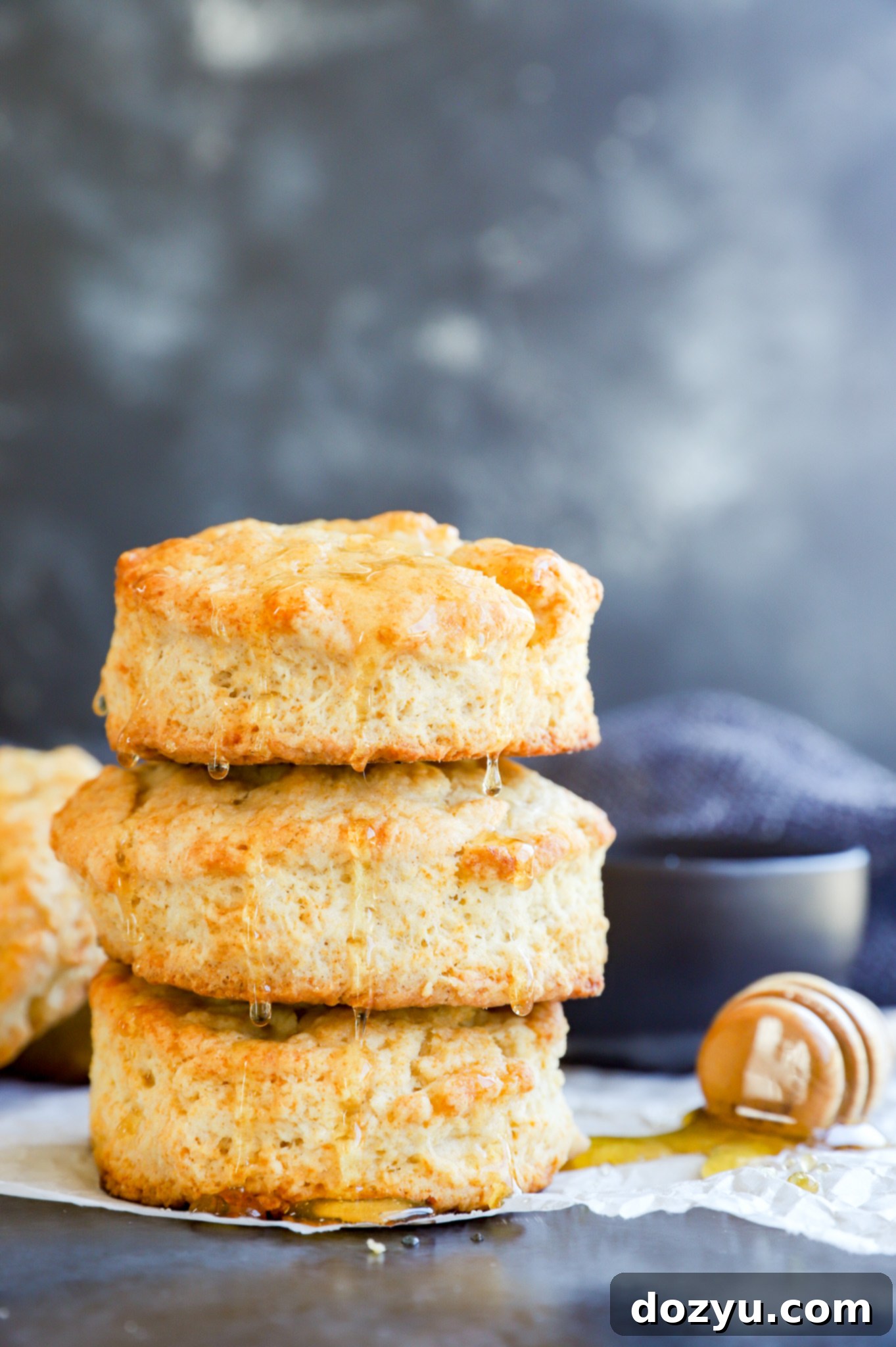 A charming photo of stacked homemade bread with a jar of honey to the side, ready for spreading.
