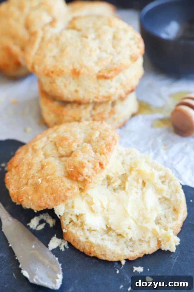 A single honey butter biscuit, gently spread with butter, resting on a rustic plate.