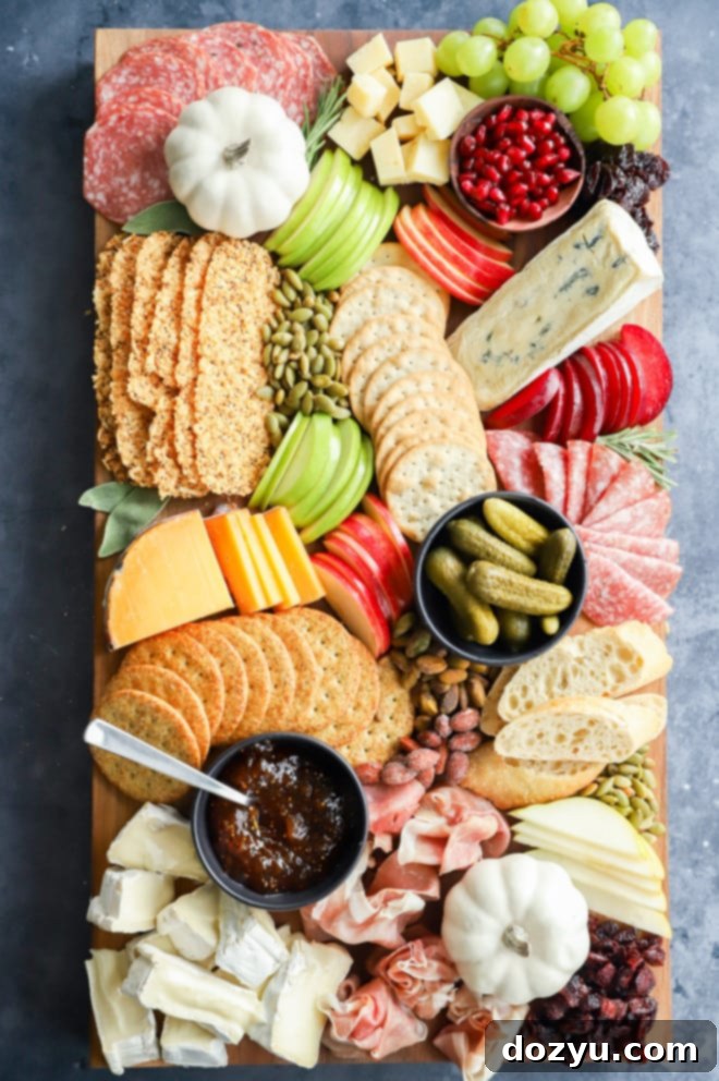 Abundant fall grazing board with various meats and cheeses, alongside fresh and dried fruits