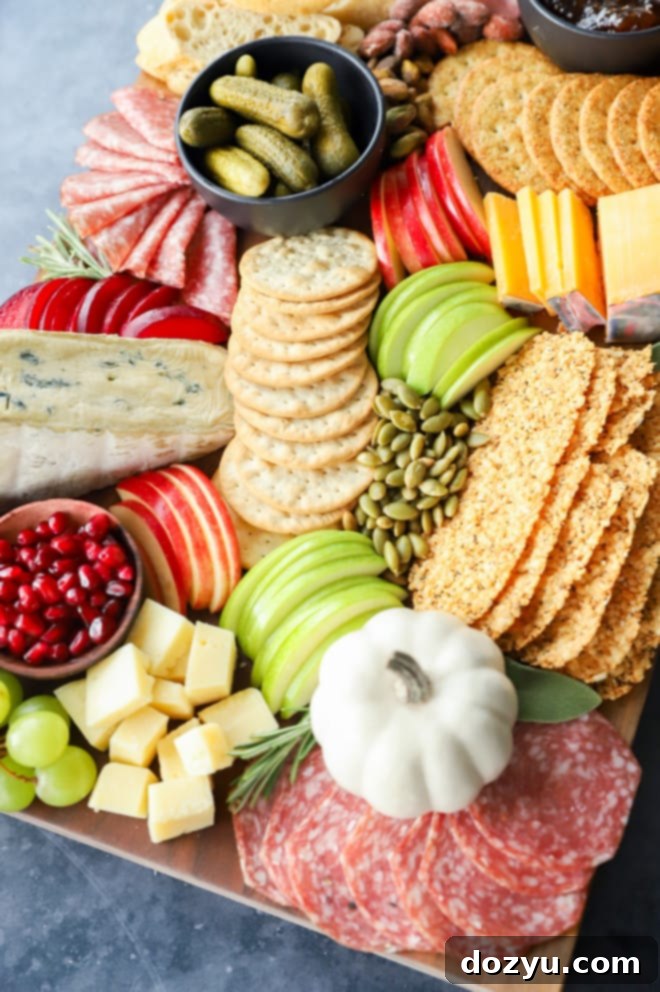 Selection of autumn ingredients like apples, pears, grapes, and crackers arranged on a wooden cutting board