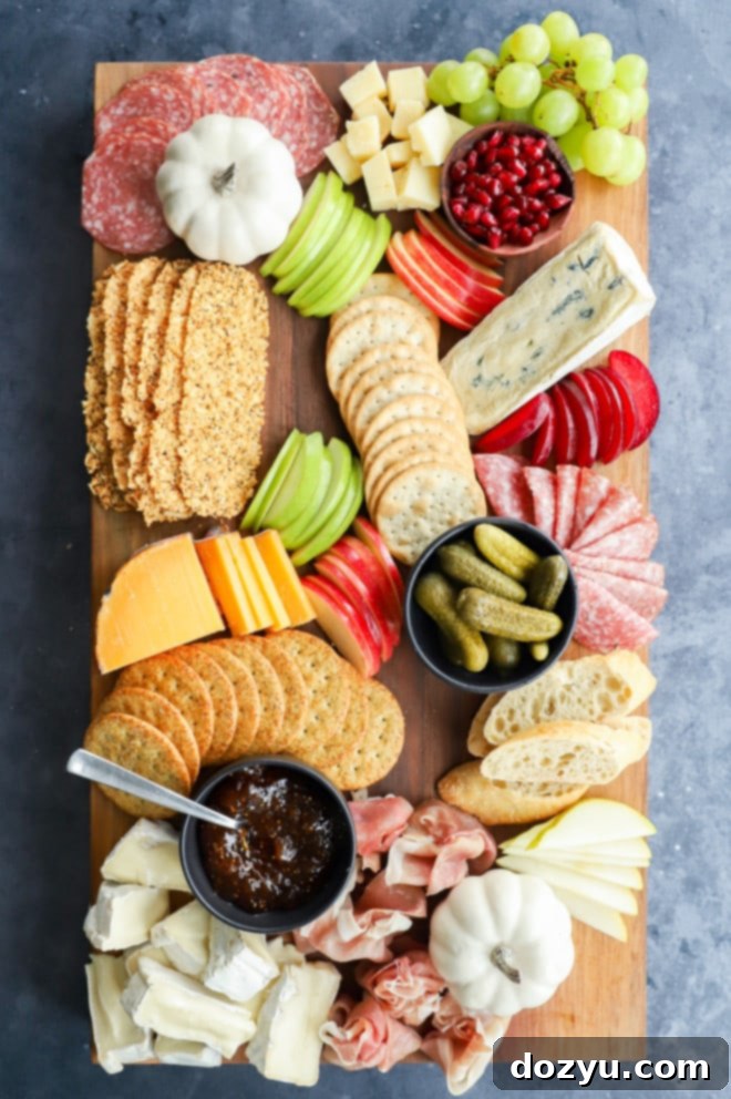 Array of fresh ingredients for a fall charcuterie board, including sliced fruits, nuts, and crackers