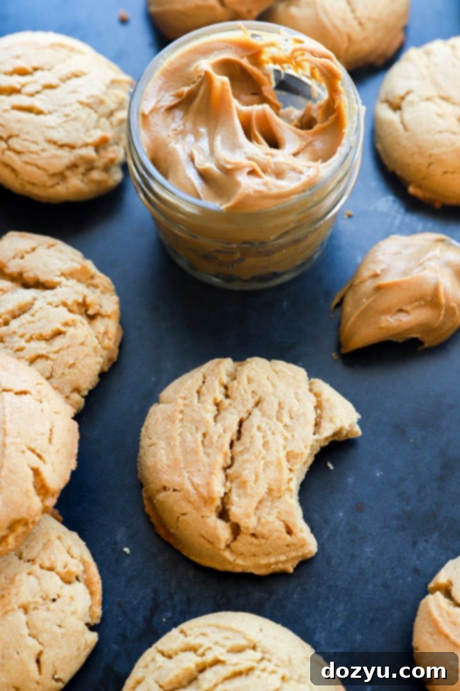 Irresistibly Chewy Peanut Butter Cookies 2 A stack of perfectly thick and chewy peanut butter cookies next to a jar of creamy peanut butter, showcasing their rich, golden-brown edges and soft centers.