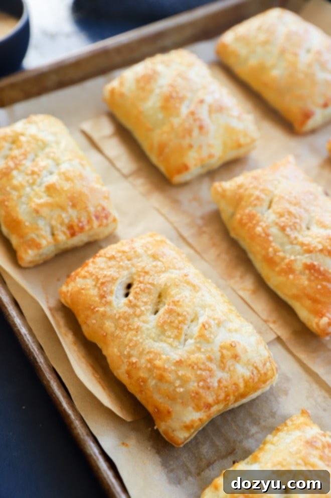 Freshly baked Nutella puff pastry pies on a baking sheet, golden and puffed.