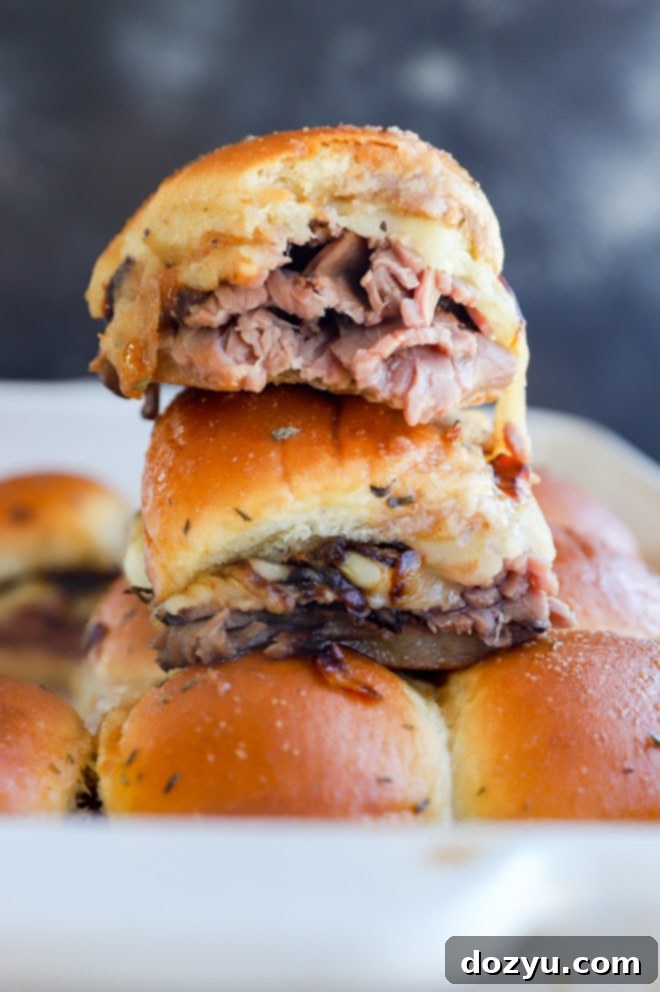 roast beef sliders on top of a baking dish, beautifully golden with melted cheese