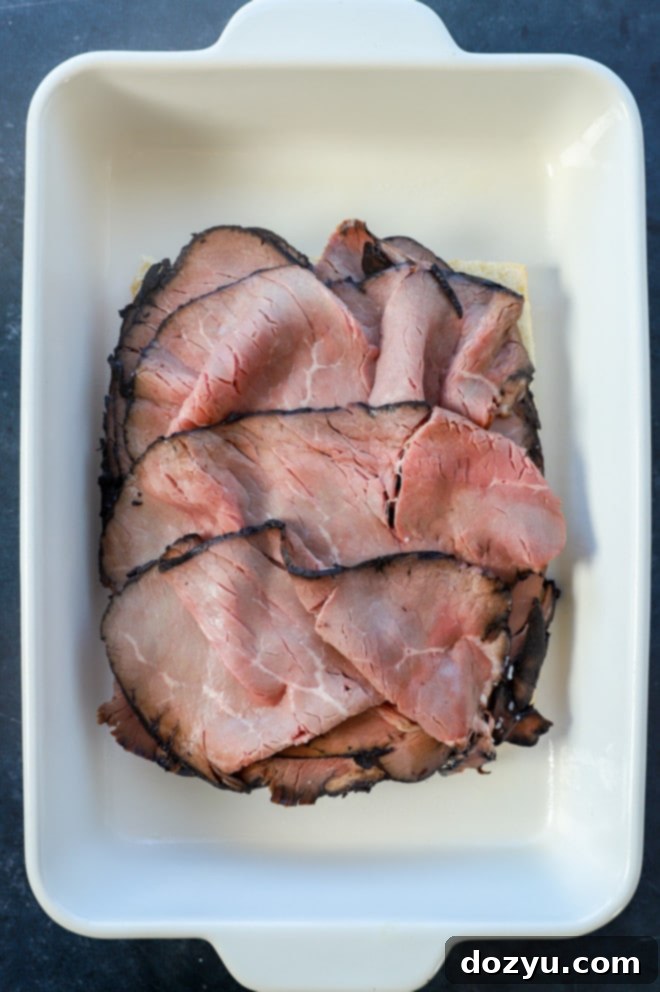 layers of thinly sliced roast beef placed over Hawaiian rolls in a baking dish