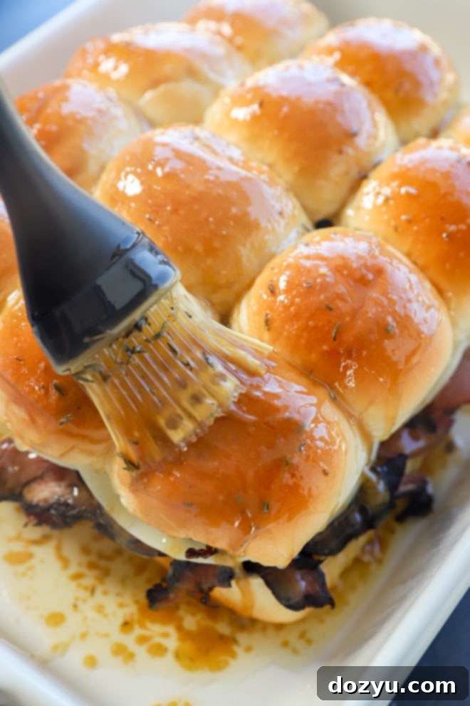brushing melted butter mixture generously on top of Hawaiian rolls filled with roast beef and cheese