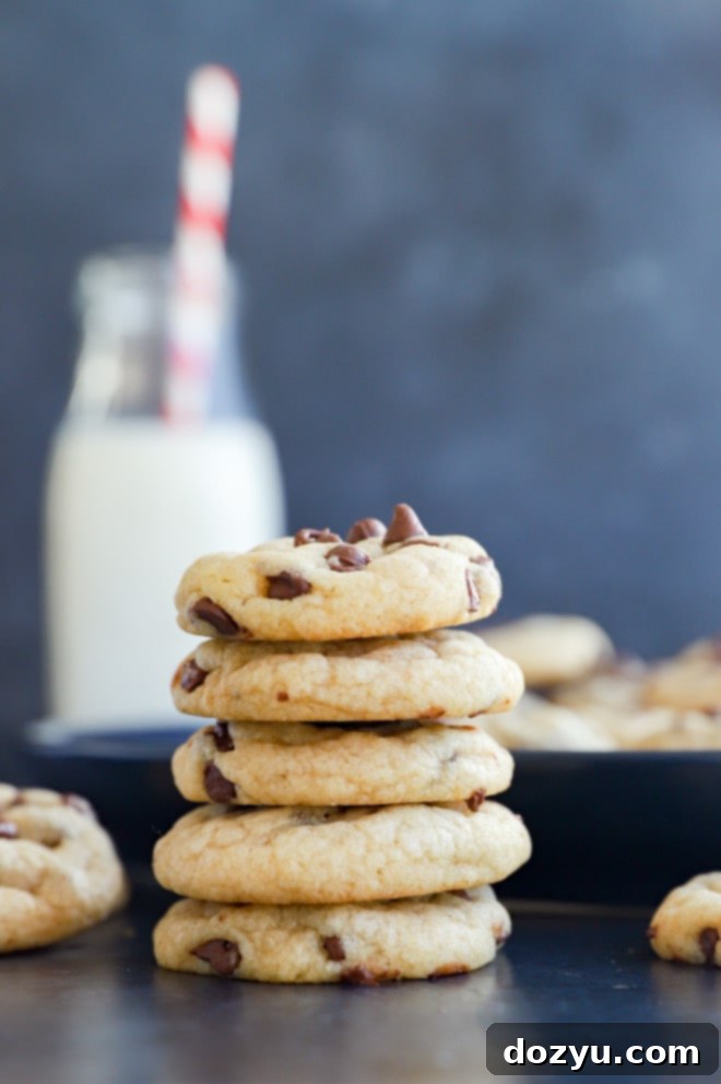 Stack of miniature chocolate chip cookies with a bottle of milk and straw beside them, ready to be enjoyed.