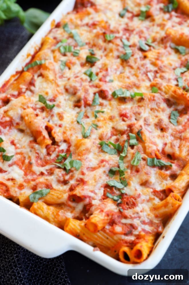 Close-up of baked pasta with melted cheese and fresh basil leaves on top