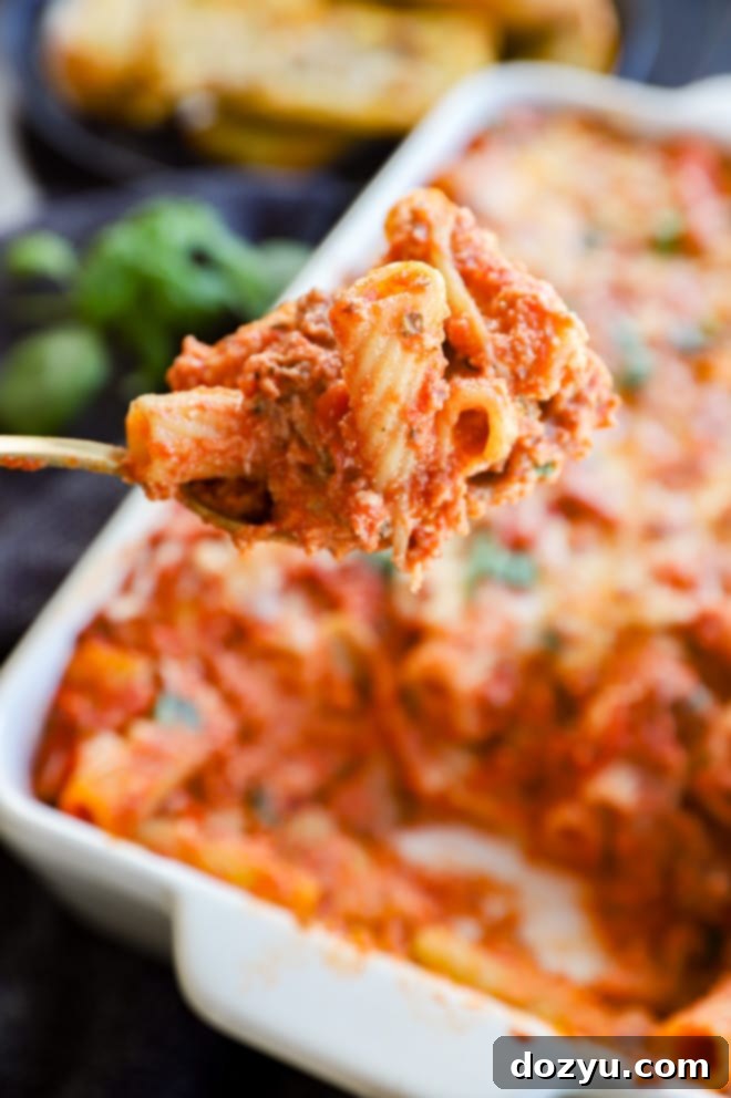 A spoonful of baked rigatoni al forno, showing extra melted cheese and rich sauce