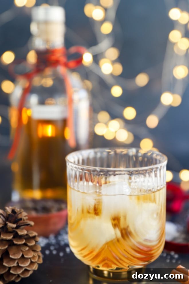 Glass of holiday cocktail over ice with lights in the background