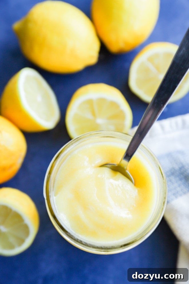 Effortless Zesty Lemon Curd 7 Close-up of creamy lemon curd in a glass jar, highlighting its smooth texture and vibrant yellow color, with fresh lemons in the background.