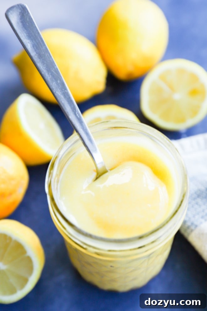 Effortless Zesty Lemon Curd 9 A spoon full of lemon curd in a glass jar, with a soft focus on the creamy texture, hinting at its deliciousness for breakfast or dessert.