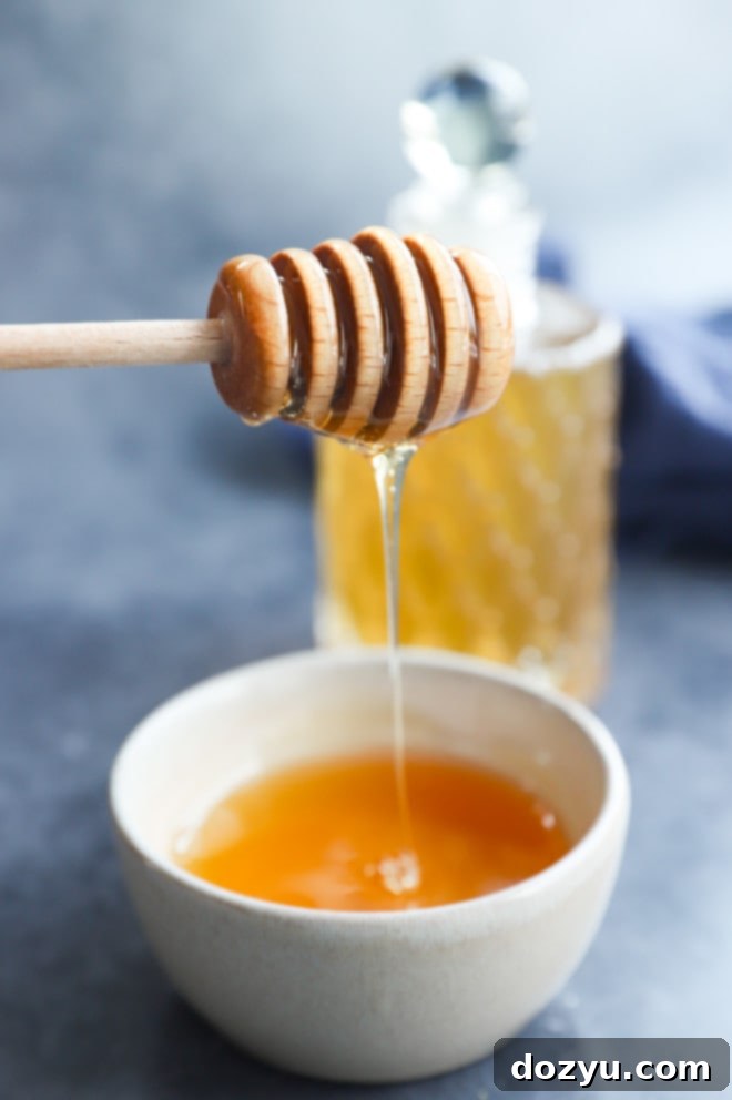 drizzling honey from a honey stick into a bowl, illustrating the natural source of the syrup