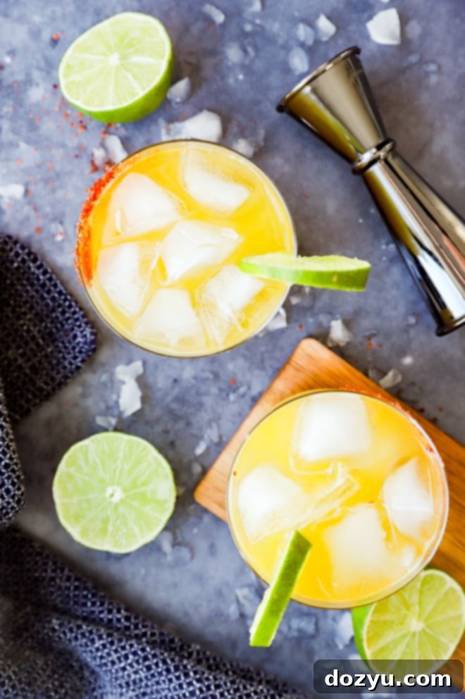 Glasses of orange cocktail with lime slices and jigger, illustrating a tropical passion fruit margarita.