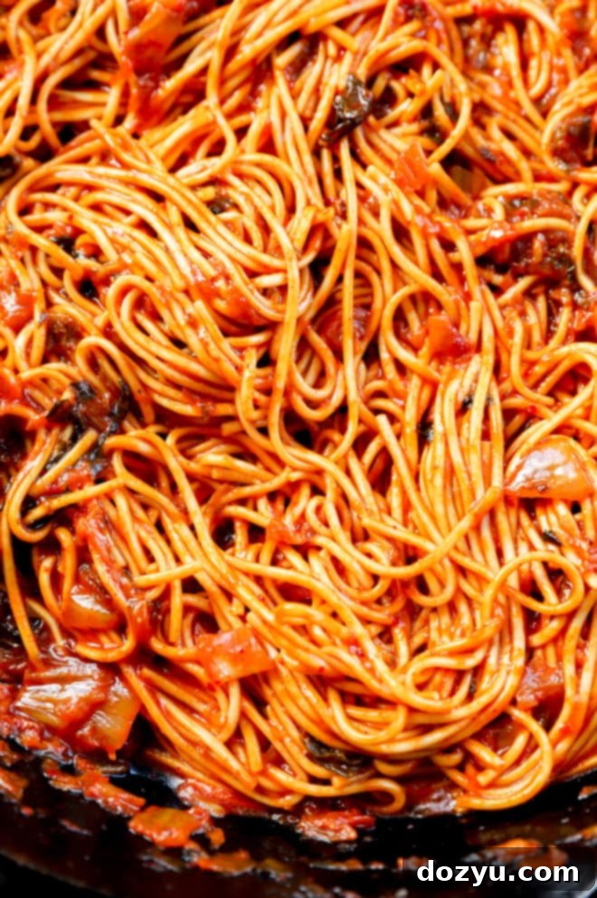 Kimchi udon cooking in a cast iron skillet, showcasing the rich sauce and noodles