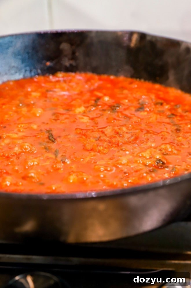 Rich kimchi and gochujang sauce simmering in a skillet, thickening to perfection