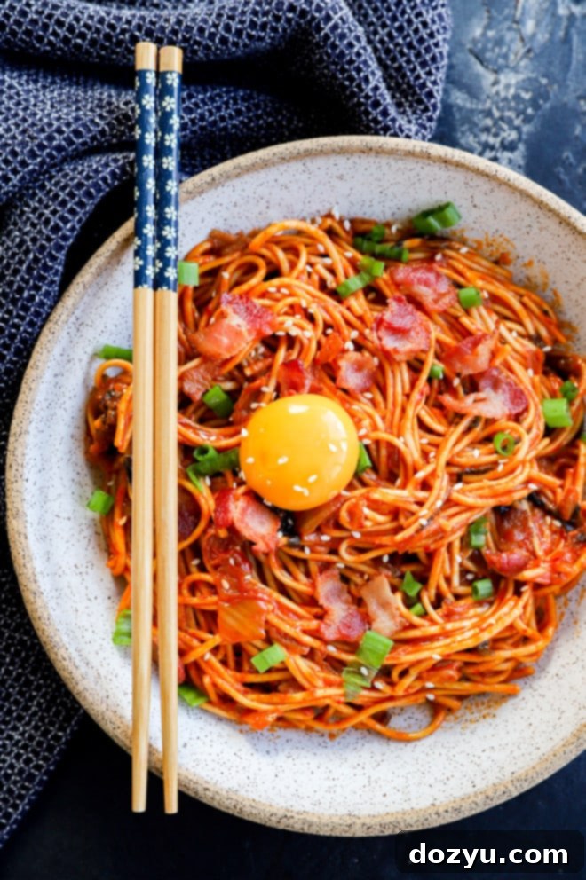 Kimchi udon served in a bowl, topped with a runny egg yolk and fresh green onions