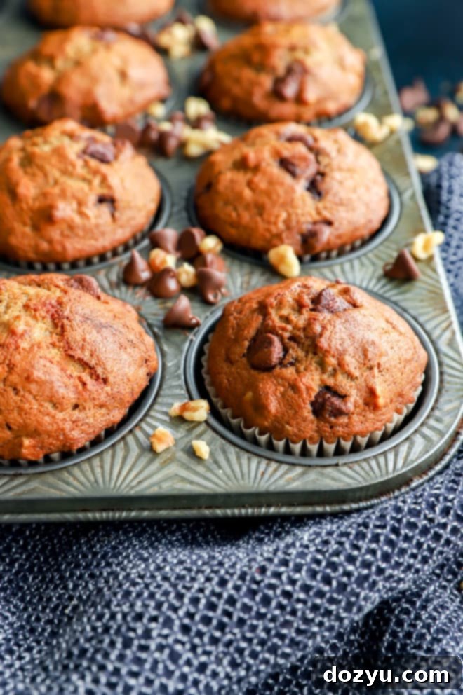 Freshly baked banana bread muffins cooling in a muffin tin, showing their golden brown tops.