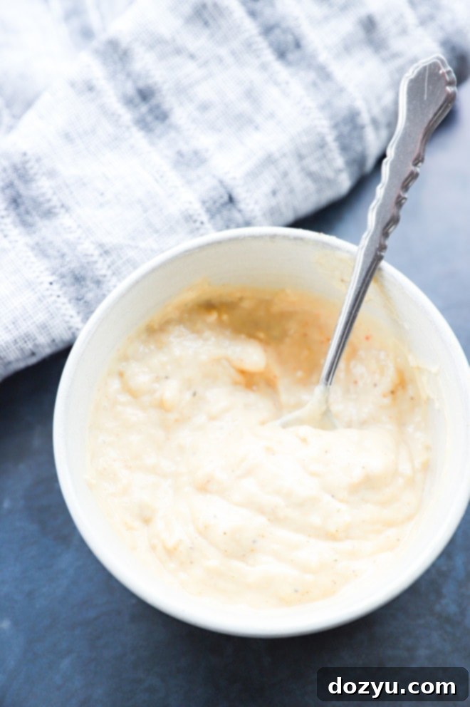 A bowl of creamy roasted garlic aioli with a spoon, ready to be enjoyed as a versatile sauce or dip.