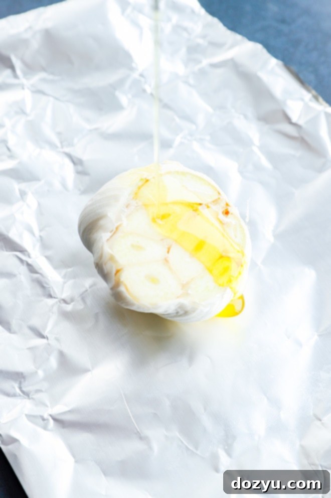A whole head of garlic drizzled with olive oil, ready for roasting.