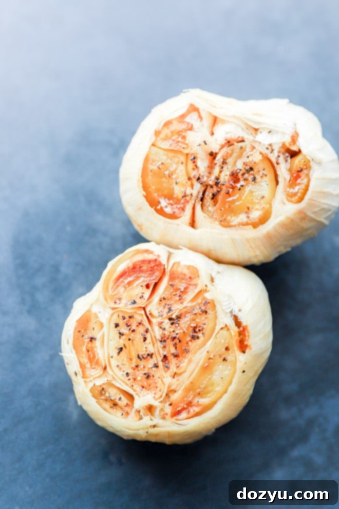 Two whole heads of beautifully roasted garlic, showing their soft, golden-brown cloves.