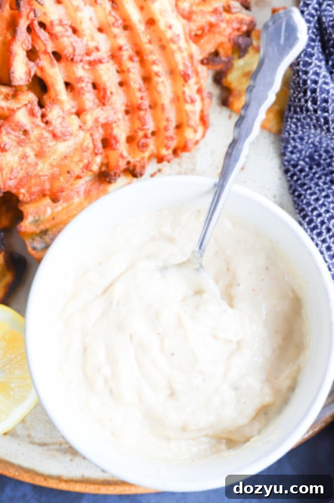 A bowl of creamy roasted garlic aioli served alongside a plate of crispy french fries, ready for dipping.