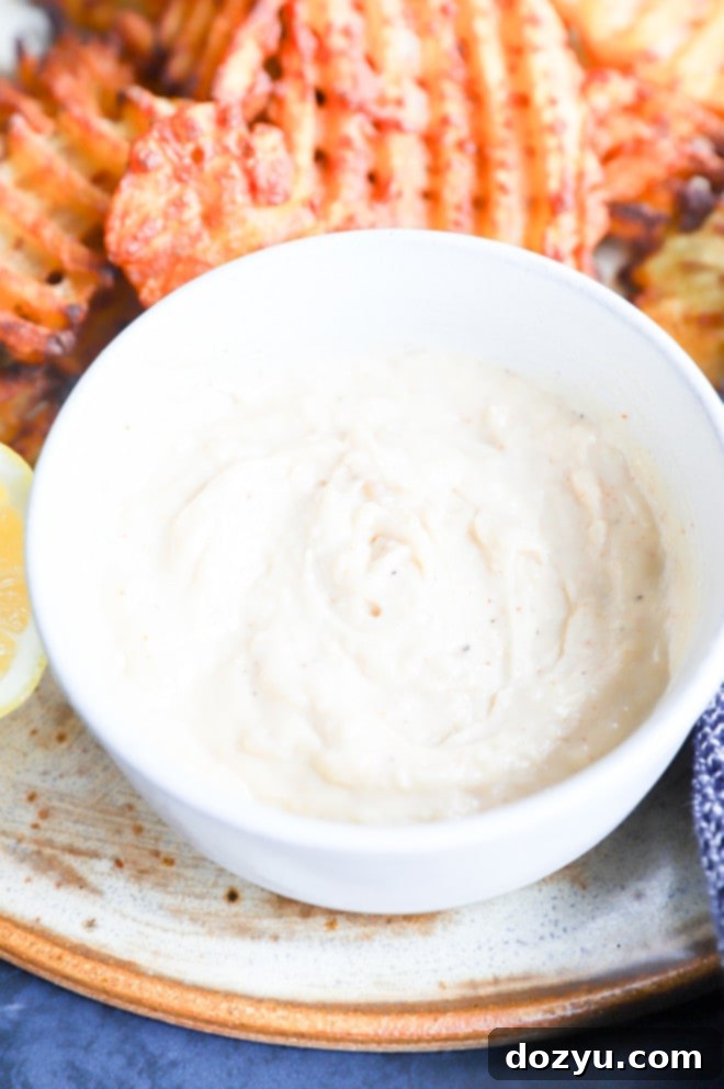 A beautifully presented bowl of savory roasted garlic aioli, ready for use as a dip or spread.