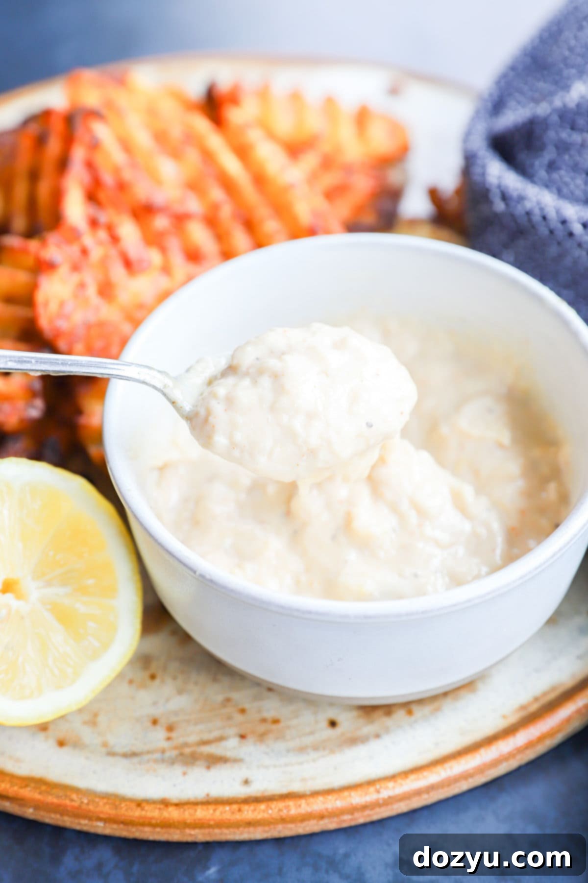 A spoonful of creamy roasted garlic aioli, showcasing its rich texture and perfect for spreading on sandwiches or dipping.