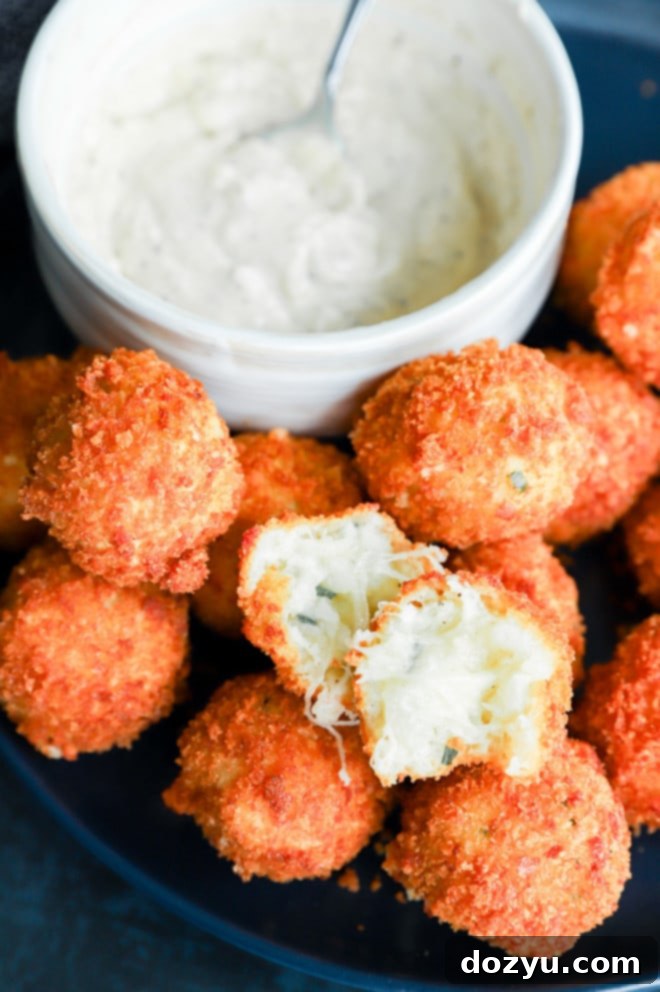 A plate piled high with crispy, golden-brown fried potato cheese balls, ready to be served as an appetizer.